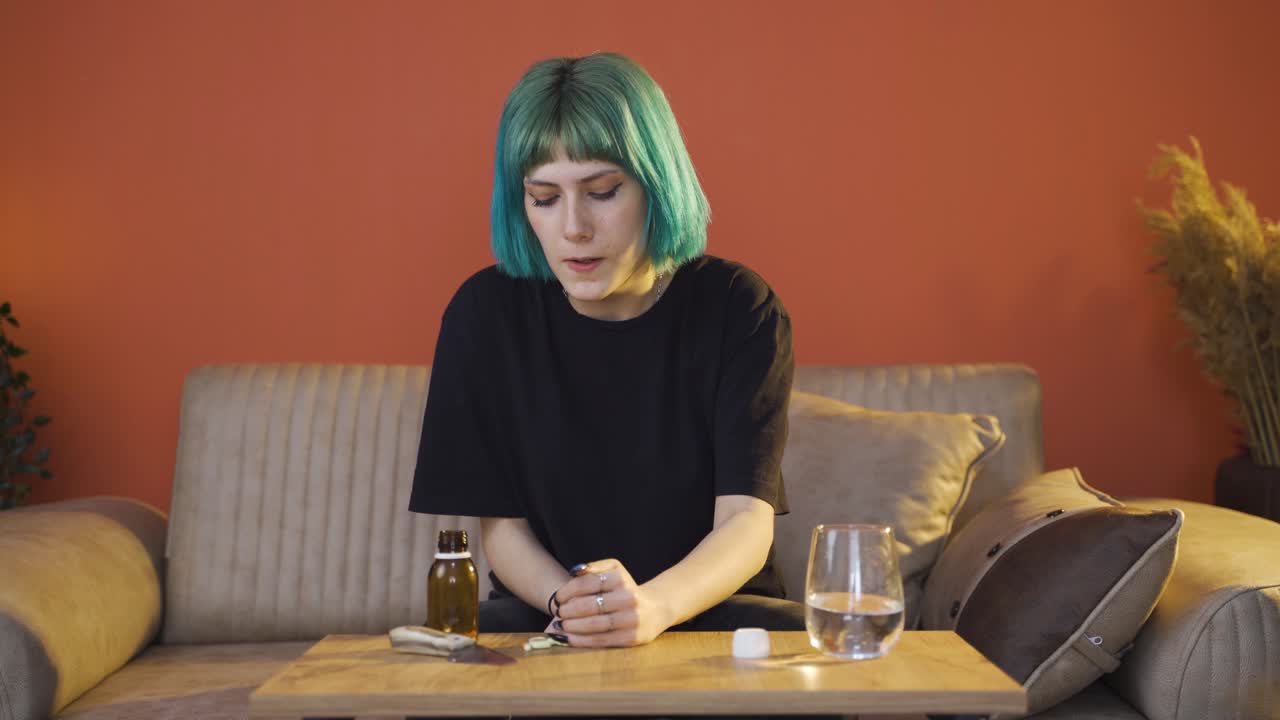 la joven que toma las pastillas en la mesa con las manos temblando. suicidio.