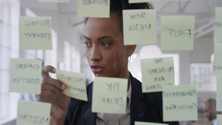 mixed race business woman using sticky notes brainstorming ideas problem solving with creative mind map planning strategy in office working on solution