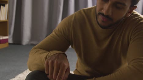 muslim man at home sitting on floor and reciting from the quran 4