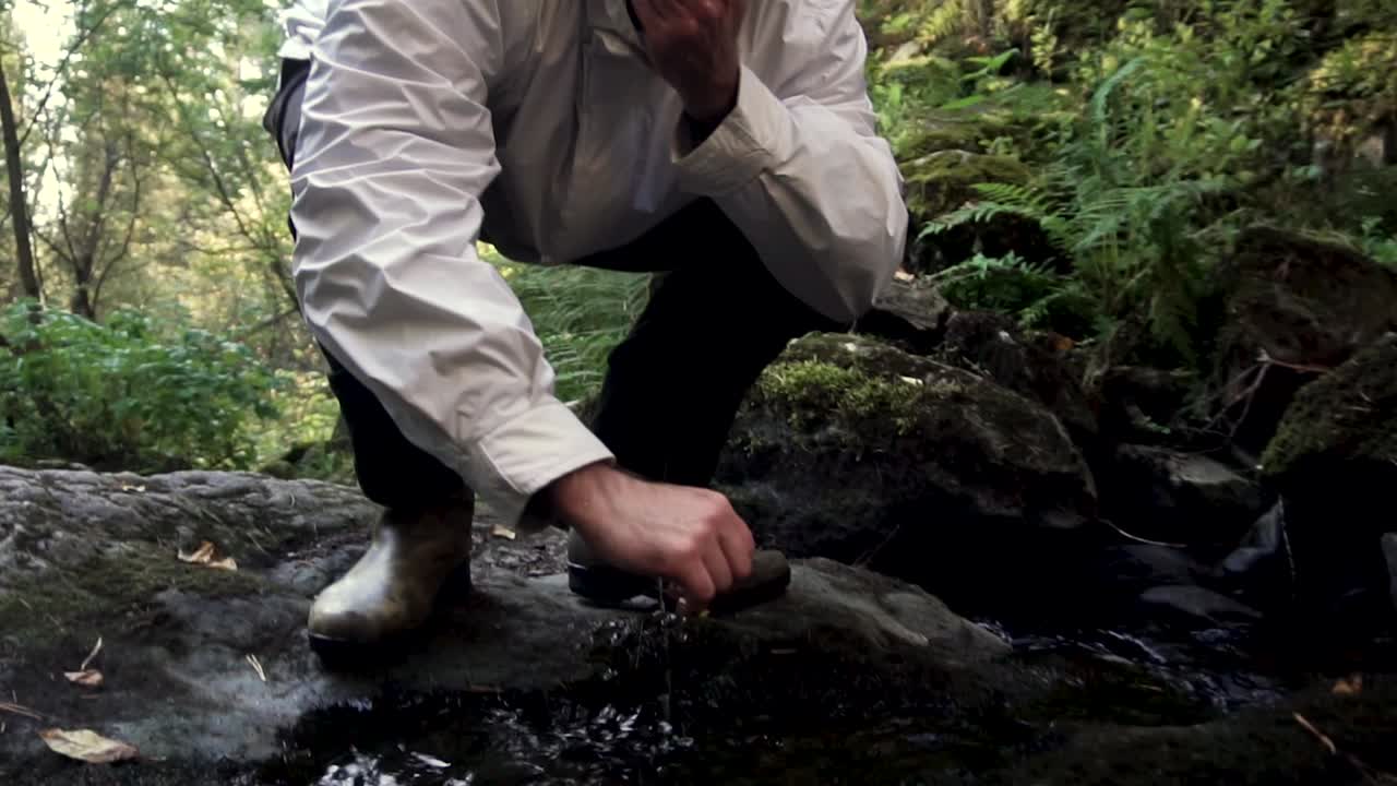 숲 속 의 하천 에서 물 을 마시는 사람