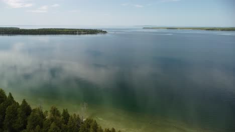 antenne rückwärts von ruhigem seewasser über bewaldeter insel, hessel, michigan