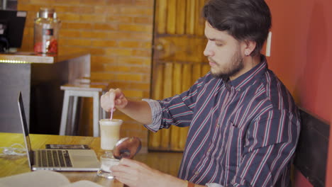chico guapo usando una computadora portátil en una cafetería