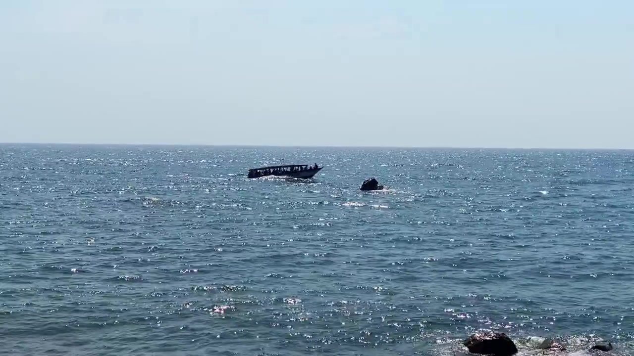 Uzak Usisya yakınlarındaki Malavi Gölü'nü geçen siluet halindeki yolcu teknesi, güneş ışığı yansımalarının hafifçe hareket eden su üzerinde parıldamasıyla