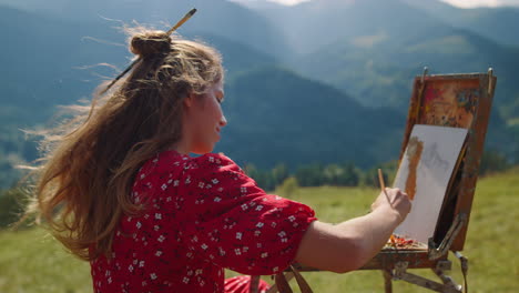 woman painter drawing mountains landscape on meadow. girl painting using easel.