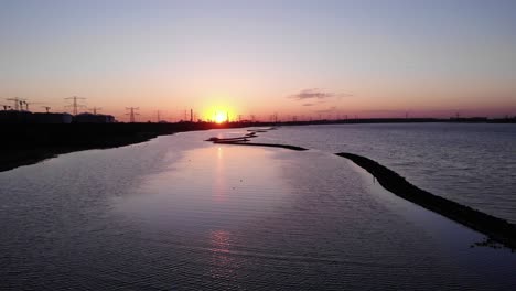 belle vue sur le coucher du soleil avec des oiseaux volant au-dessus des eaux tranquilles à maasvlakte à brielse meer, pays-bas