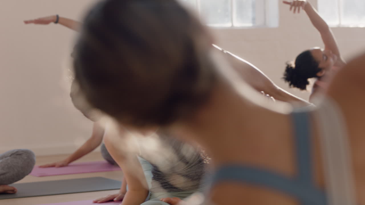 아름다운 여성의 요가 수업은 일출 시 그룹 명상을 가르치는 피트니스 스튜디오 강사에서 건강한 라이프스타일을 즐기는 앉아 있는 측면 굴곡 자세를 연습합니다.