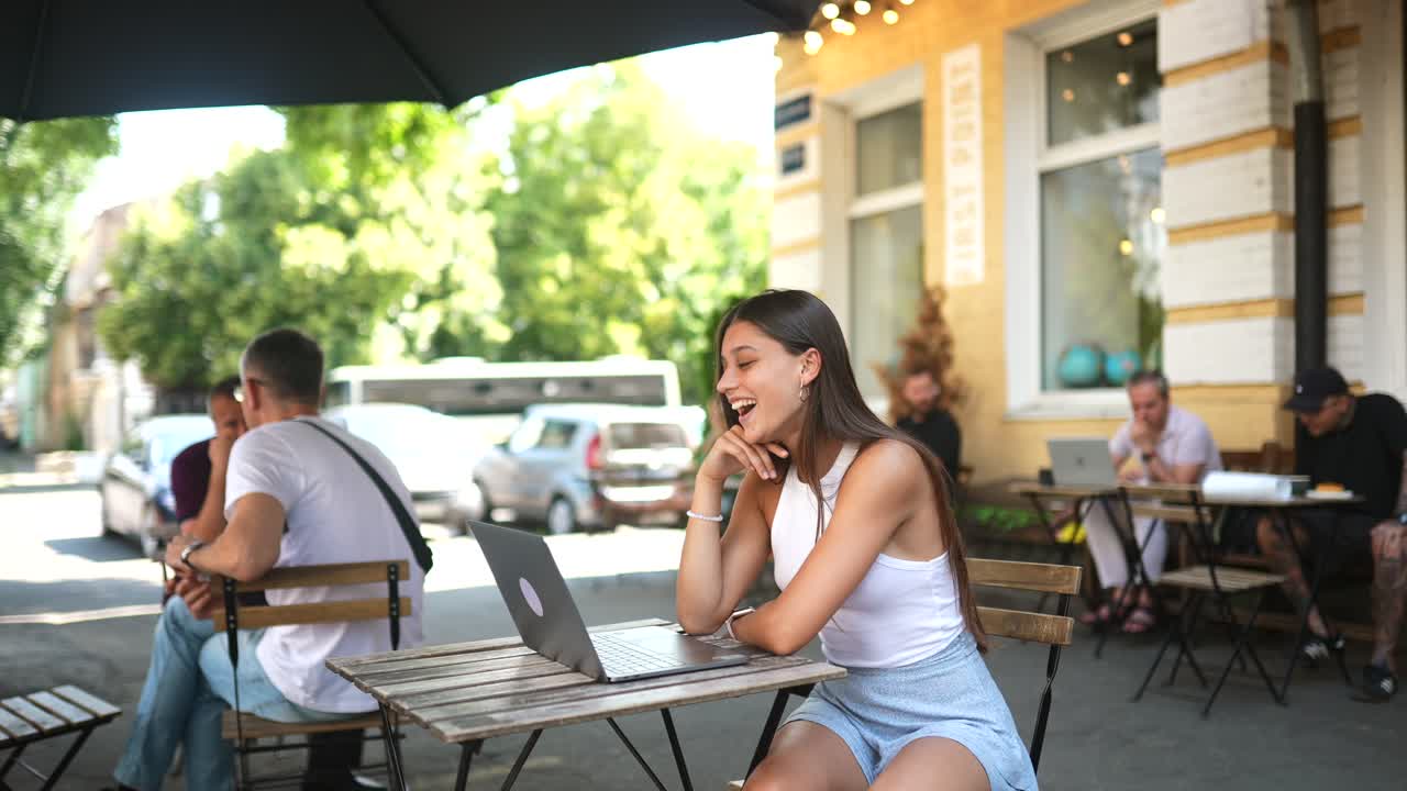 Giovane donna che lavora al laptop in un caffè all'aperto
