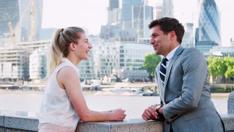 businesspeople standing by river thames and london city skyline