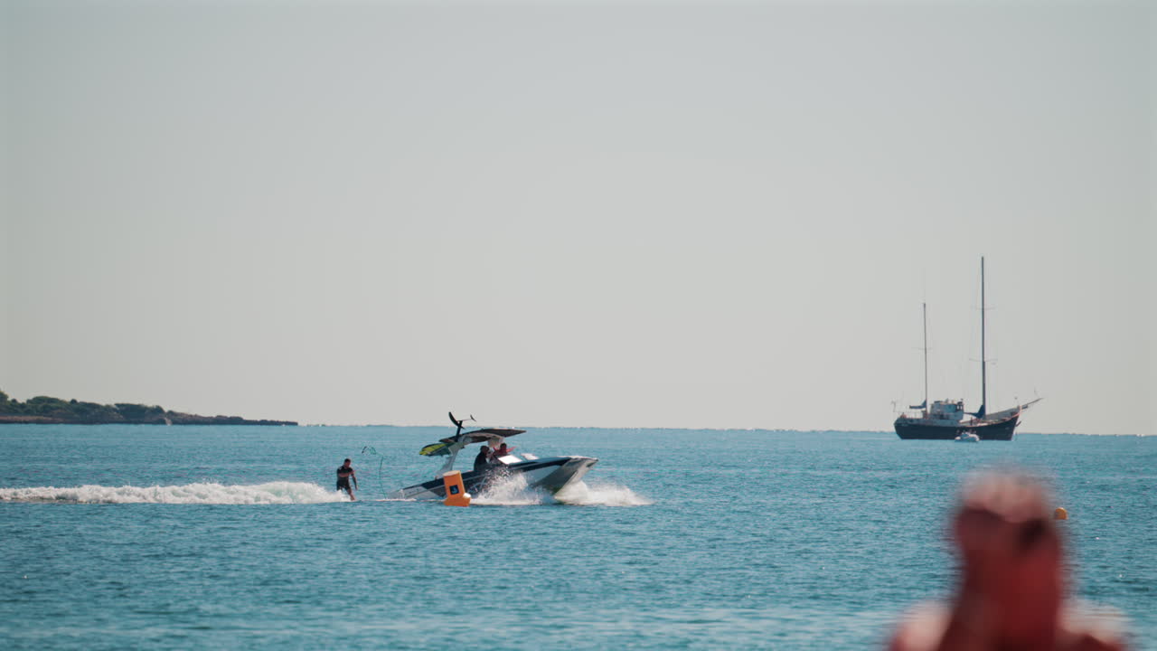 Cannes, France - October 7, 2025: A fast motorboat pulls an inflatable raft across the calm blue sea, while distant yachts rest on the horizon