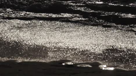 Slow-motion-waves-lap-on-dark-beach-at-night