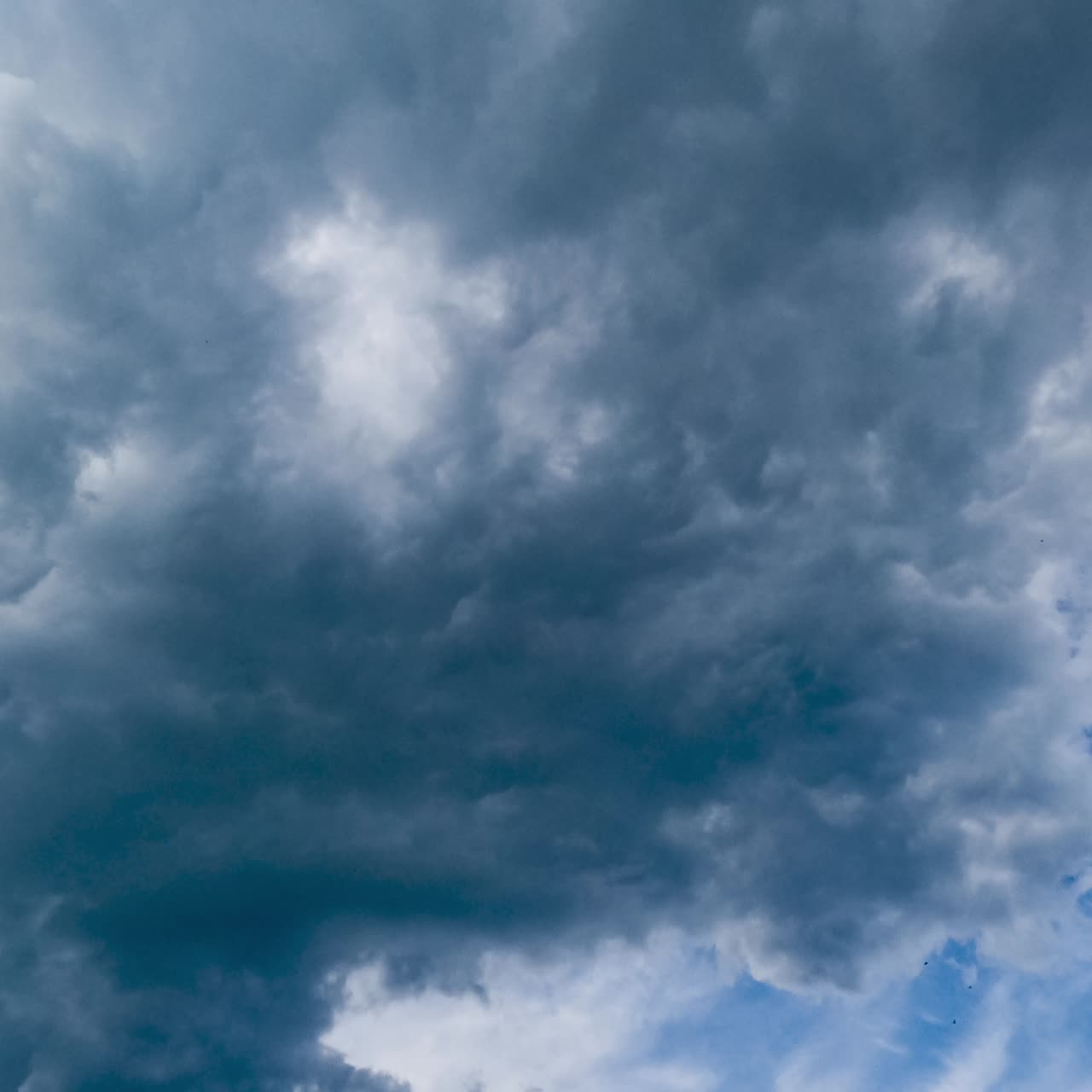 Grey cumulus clouds transforming in atmosphere. Heavy clouds go away and light spindrift clouds extending by the blue sky. Timelapse