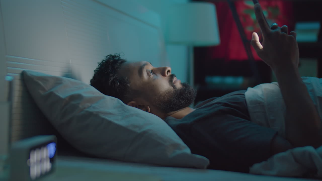 Man Using Phone and then Sleeping in Bed at Night