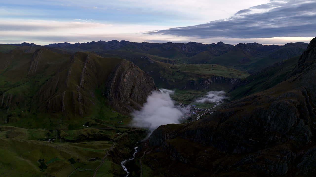 Cinematic aerial view of snowy Andes mountains in Peru with glaciers, rocky cliffs, and hidden blue alpine lake under misty clouds, dramatic landscape and natural travel destination