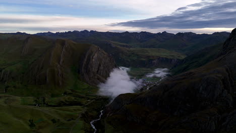 Cinematic aerial view of snowy Andes mountains in Peru with glaciers, rocky cliffs, and hidden blue alpine lake under misty clouds, dramatic landscape and natural travel destination