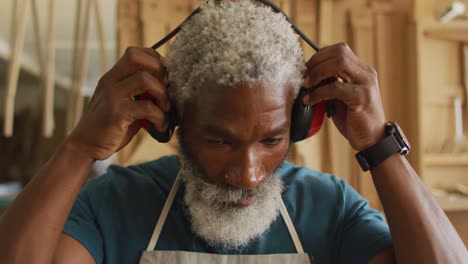 portrait of african american male carpenter wearing protective ear-muffs in a carpentry shop