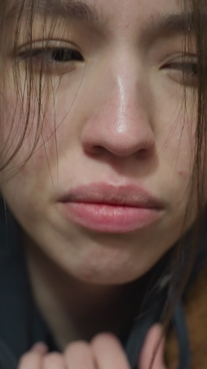 Close-up shot of a grieved girl in a brown coat, standing in an underpass tunnel. Her expression conveys deep sadness and emotional turmoil, creating a somber and reflective mood in the urban setting