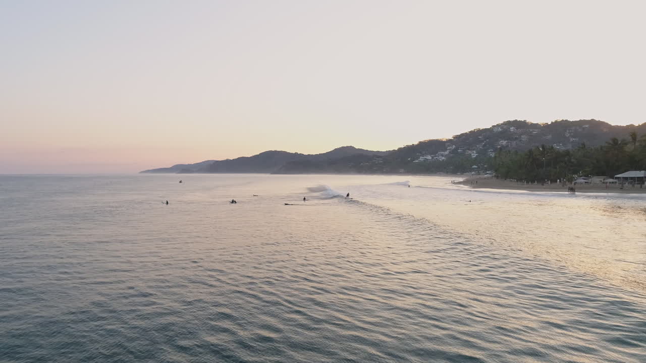 서퍼들이 해안을 향해 질주할 때 파도를 따라가는 넓은 공중 추적 샷, 4k