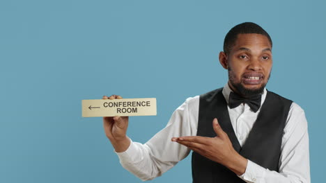 hotel concierge using a wall indicator to guide clients to the conference room