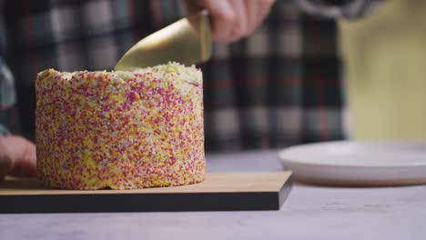 Nahaufnahme-Einer-Person-Zu-Hause,-Die-Ein-Stück-Vom-Regenbogenfestkuchen-Auf-Tisch-2-Schneidet