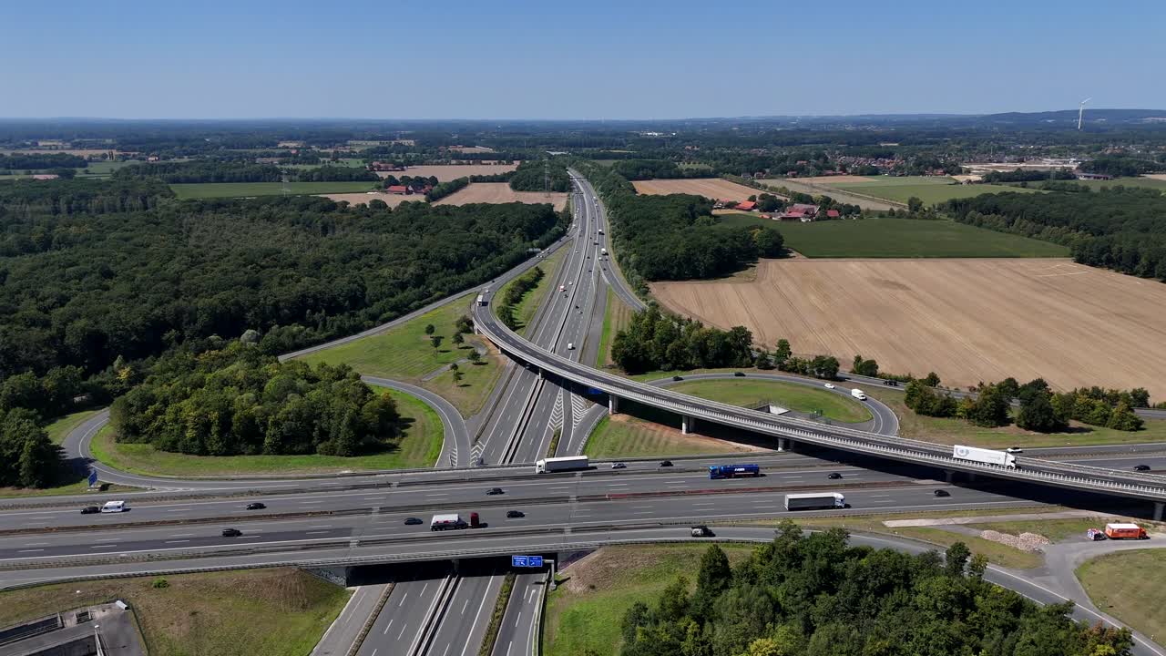 Elevated autobahn interchange in Germany suburb. Bridge and road with busy cars in summer. Aerial wide shot. Forest and rural landscape in countryside