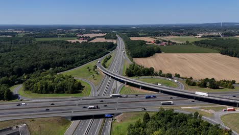 elevated autobahn interchange in germany suburb. bridge and road with busy cars in summer. aerial wide shot. forest and rural landscape in countryside