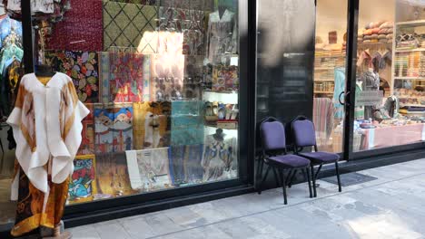 a storefront of a fabric and textile shop with a mannequin and chairs outside