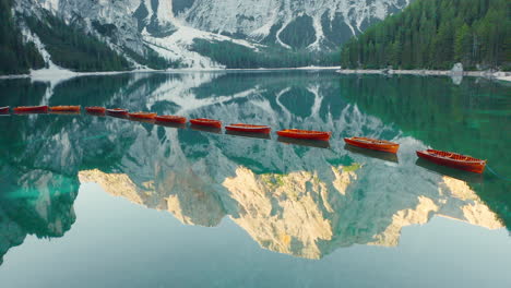 revelación épica de prags dolomitas iluminadas por el sol reflejadas en la superficie de vidrio del lago di braies, italia, antena