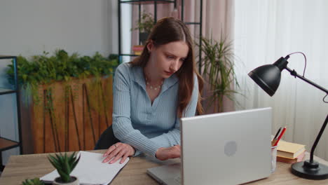 Young-businesswoman-analyzing-documents,-contract-invoices-or-graphics-report-and-working-on-laptop