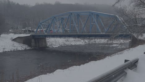 blue arched steel bridge crossing the roundout creek on a snowy day in rosendale, new york