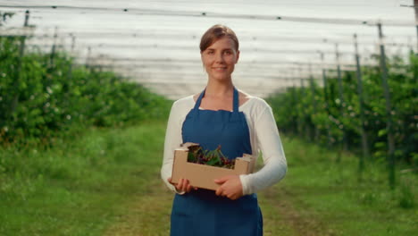 Woman-gardener-looking-camera-at-agriculture-modern-green-house-in-summer.