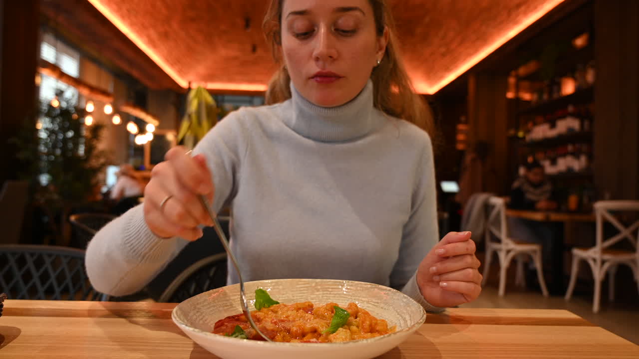 Woman eating italian gnocchi with tomatoes in a restaurant
