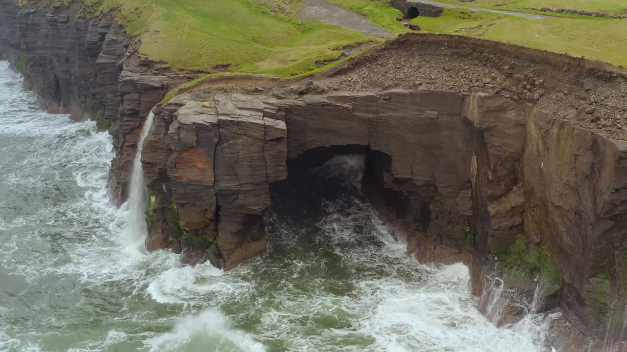 Aerial pan across Cliffs of Moher in Doolin on a rough day, showcasing dramatic cliff faces and wild sea