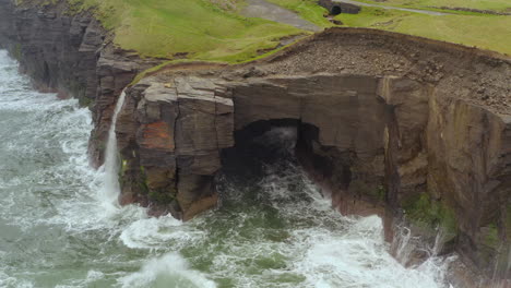 aerial pan across cliffs of moher in doolin on a rough day, showcasing dramatic cliff faces and wild sea