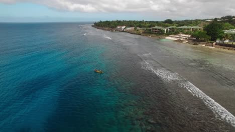 aerial revealing view of exotic island coastline and small boat in shallow water of tropical sea