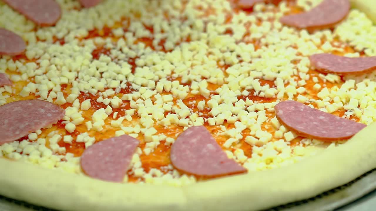 요리사는 흡연 소시지와 베이컨으로 피자를 준비하고 소시지를  ⁇ 습니다.