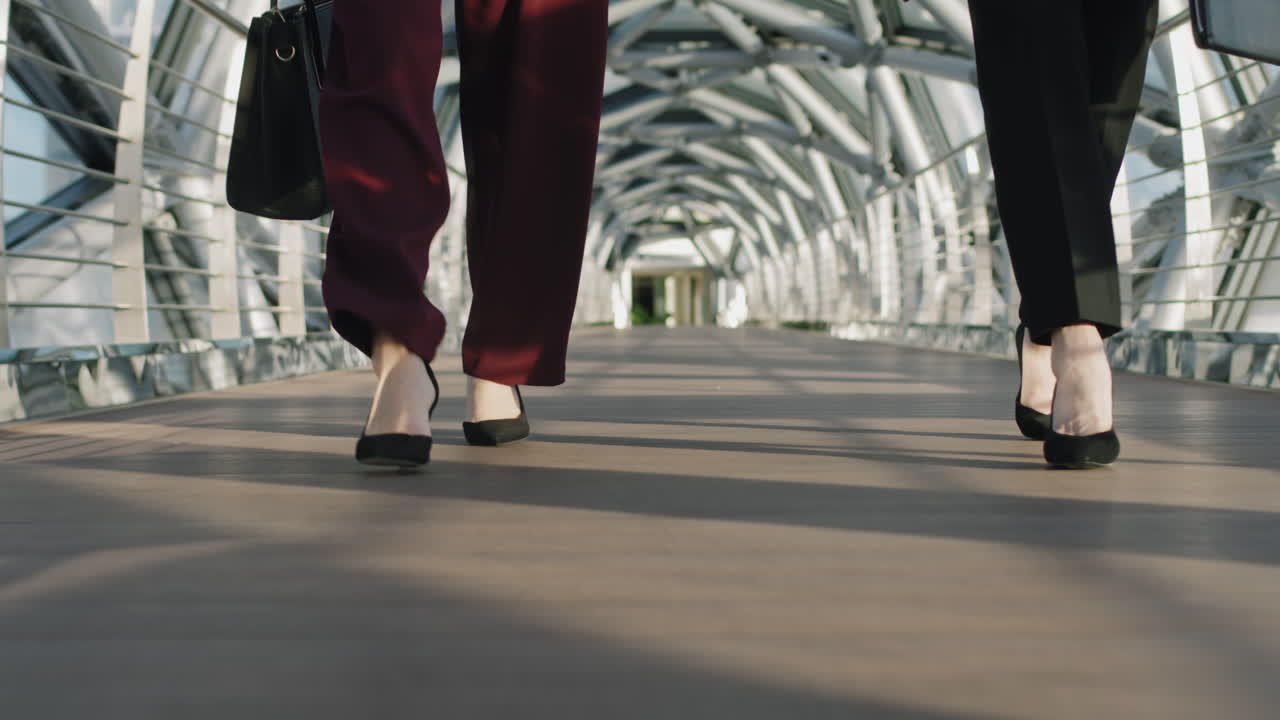 Heels Of Businesswomen Walking Along Glass Walkway