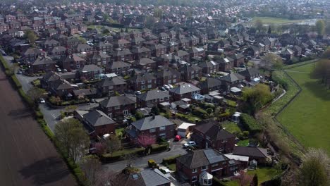 Countryside-housing-estate-aerial-view-flying-above-UK-village-farmland-residential-community-homes-slow-descend