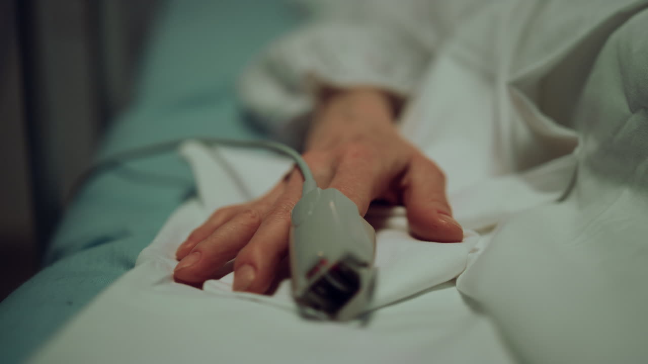 Pulse oximeter patient finger in ward closeup. Hospital emergency care unit.