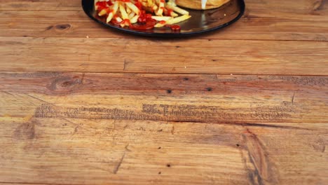 primer plano detallado de una hamburguesa de hongos acompañada de patatas fritas de ketchup, siendo removida y colocada en una mesa