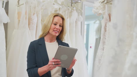 Mature-Female-Owner-Of-Bridal-Wedding-Dress-Shop-With-Digital-Tablet