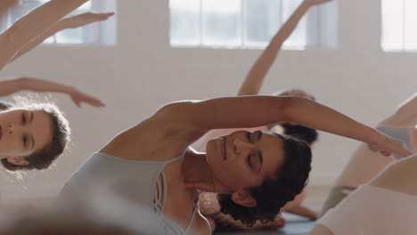 yoga-class-healthy-hispanic-woman-practicing-seated-side-bend-pose-with-group-of-beautiful-women-sitting-on-exercise-mat-enjoying-healthy-lifestyle-training-in-fitness-studio-at-sunrise