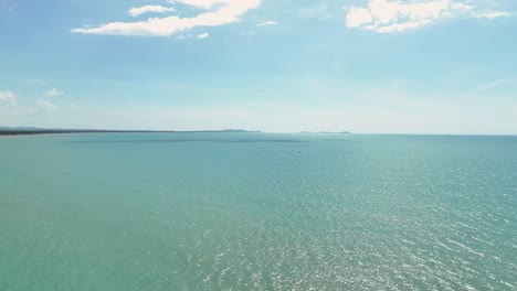 Rising-aerial-overview-of-open-ocean-and-empty-sea-water-on-clear-blue-sky-day