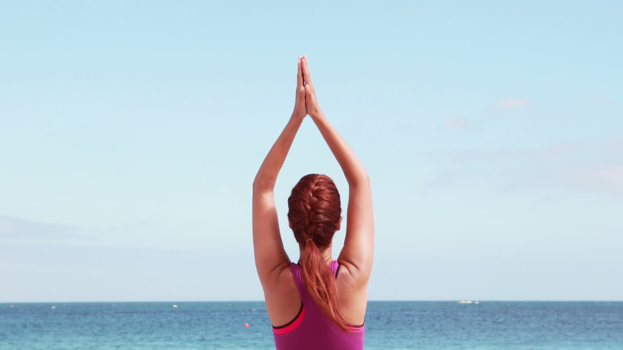 Mujer haciendo yoga en la playa