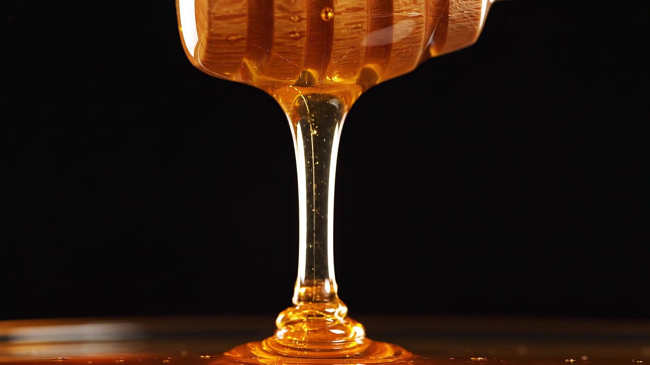 Miele dorato che cola da un mestolo di legno su sfondo nero