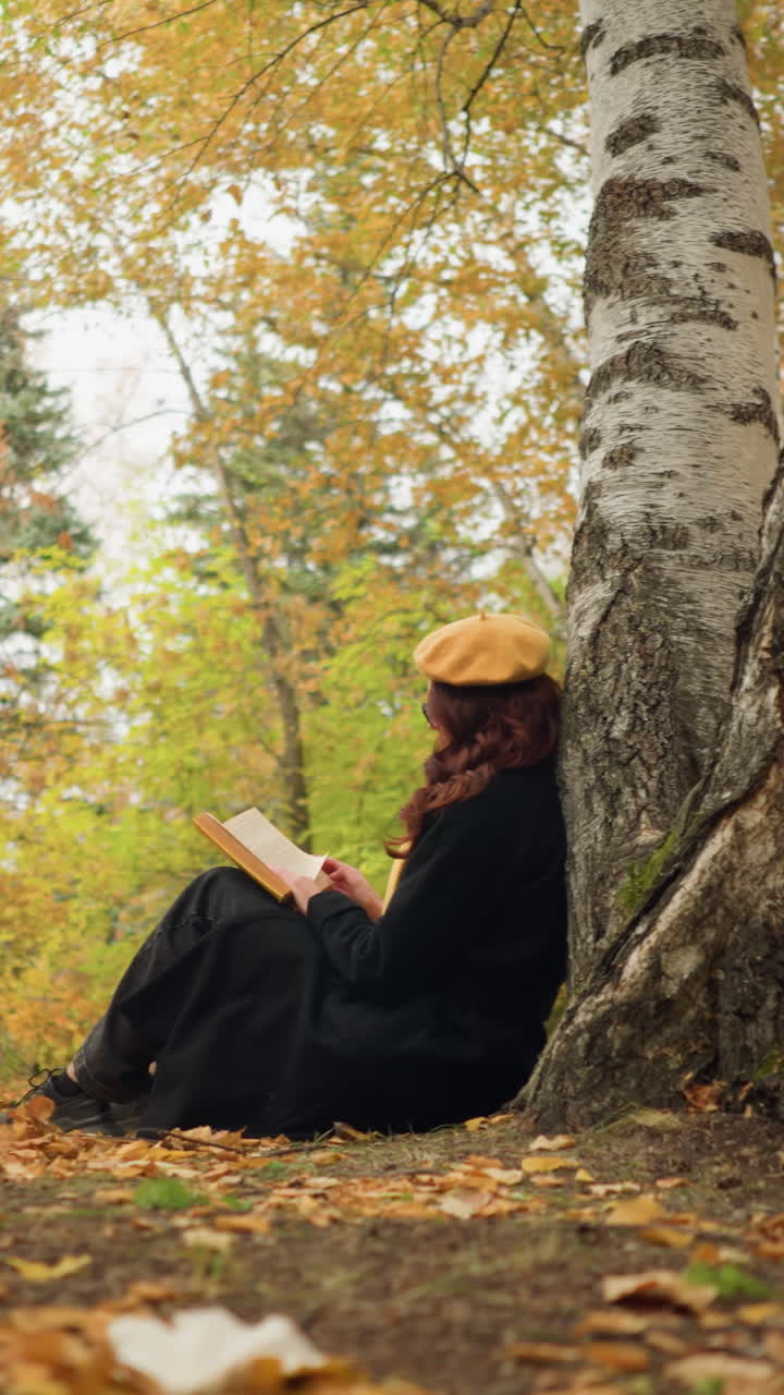 vista lateral de una dama leyendo un libro en paz y soledad, apoyándose en un árbol, rodeada de doradas hojas de otoño y un bosque exuberante, disfruta de un retiro tranquilo, sumergiéndose en la literatura