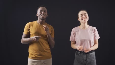 multiethnic young friends dancing on black background.