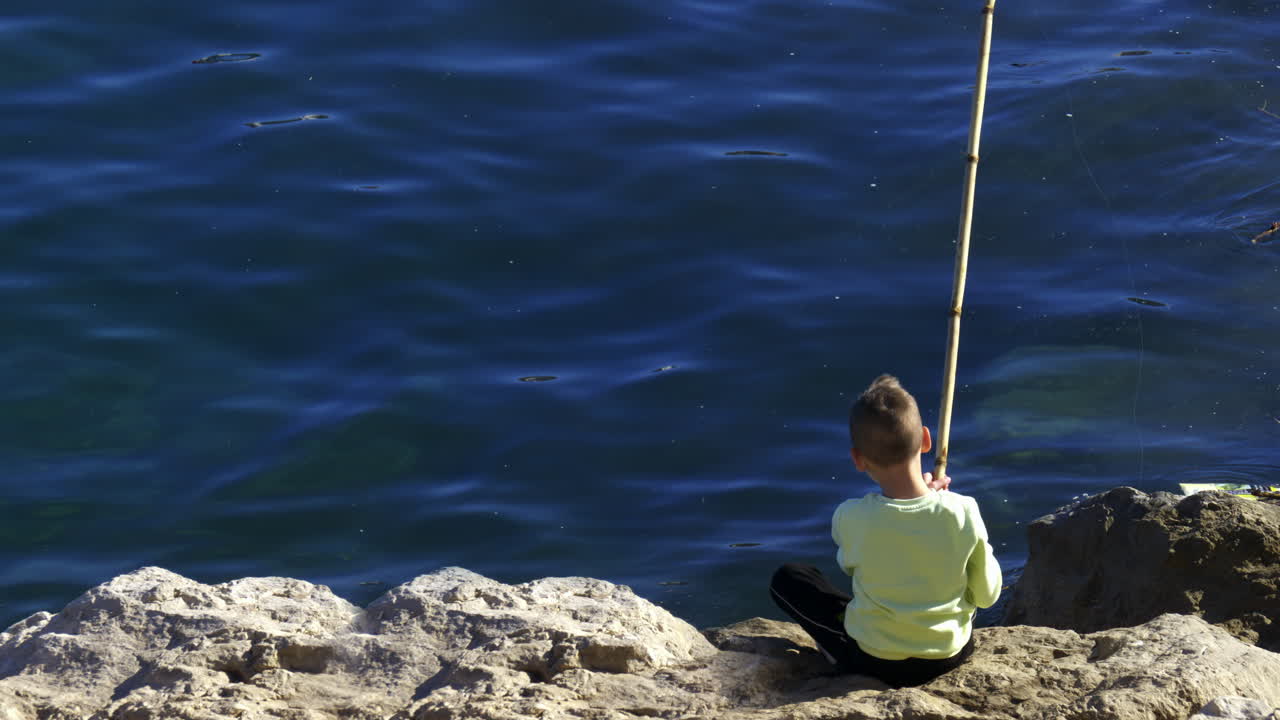 Little kid fishing in the Ligurian Sea in daylight