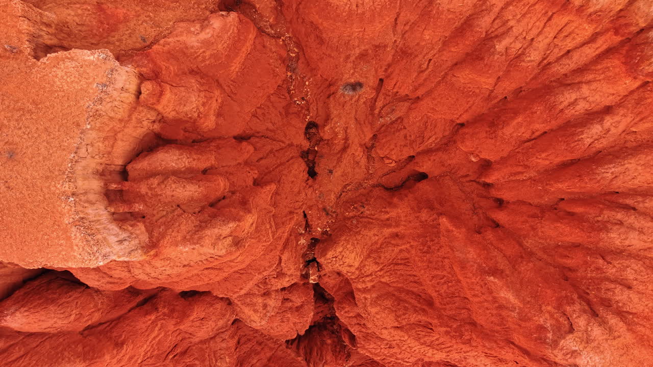 Vista dall'alto di calanchi rossi erosi e burrone. Vista aerea da drone di calanchi di argilla rossa con calanchi ramificati, detriti rocciosi e pendii texturizzati.