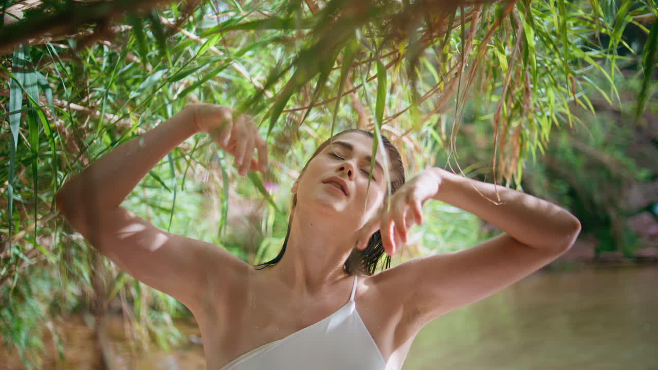 조용한 소녀는 자연을 즐기고 푸른 열대 우림 호수에서 신선한 공기를 흡수합니다.