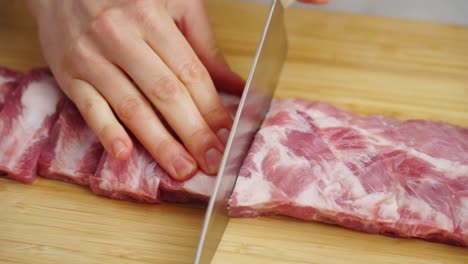 crop housewife cutting raw ribs